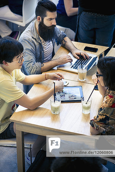 Freunde  die digitale Tablet- und Laptop-Computer im Cafe benutzen