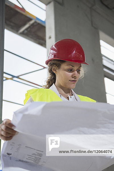 Female architect reviewing blueprint at construction site