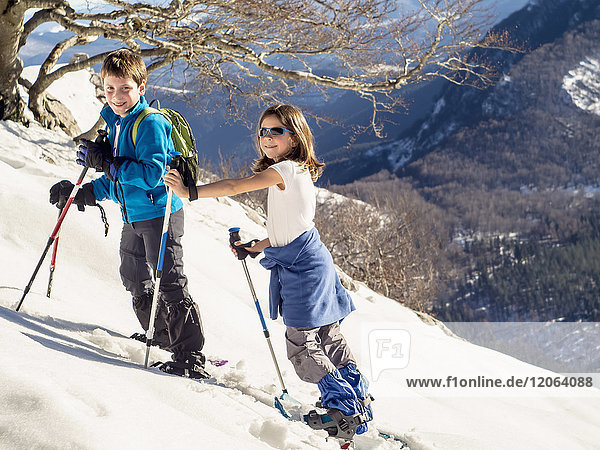 Junge und Mädchen mit Schneeschuhen beim Spaziergang über das Schneefeld am Berg Anboto