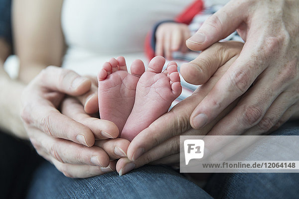 Eltern halten die Füße ihres neugeborenen Jungen