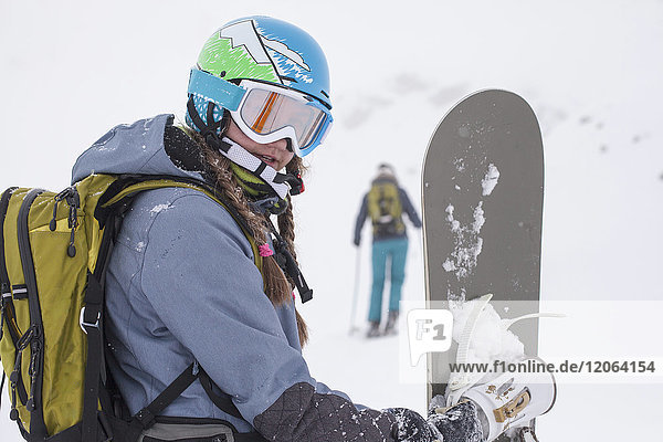 Nahaufnahme eines Mädchens in Skikleidung mit Snowboard