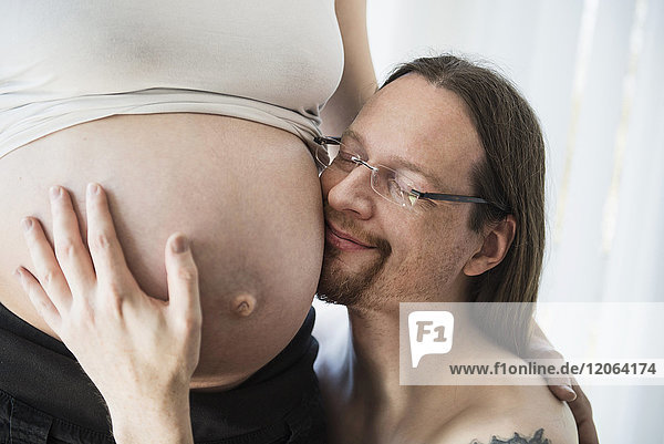 Mann berührt schwangeren Bauch seiner Frau