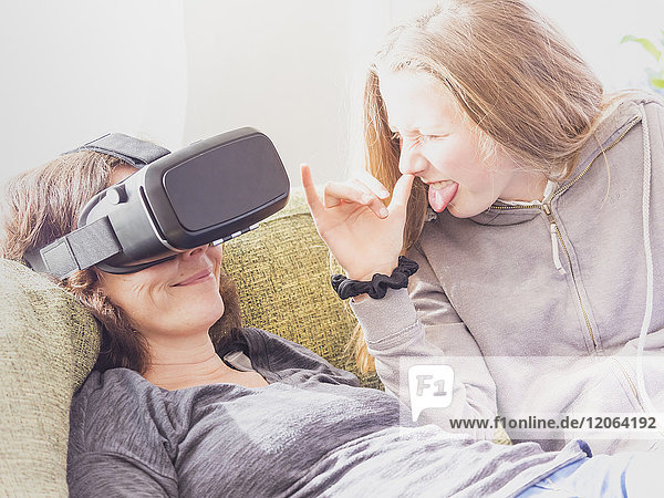 Schelmisches Mädchen mit Mutter  die ein Virtual-Reality-Headset benutzt
