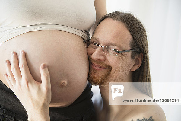 Porträt eines Mannes  der den Bauch seiner schwangeren Frau berührt