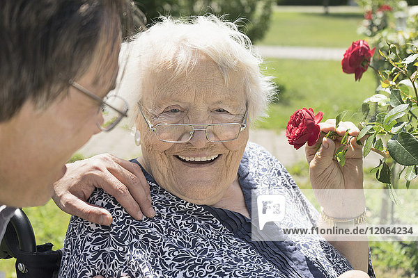 Sohn mit Mutter riecht an Rosenblüten im Park