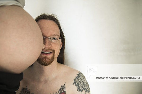 Porträt eines Mannes mit dem Bauch seiner schwangeren Frau