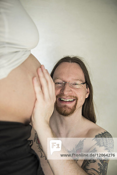 Porträt eines Mannes  der den Bauch seiner schwangeren Frau berührt