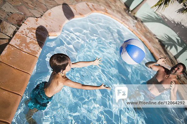 Father and son playing with ball in swimming pool