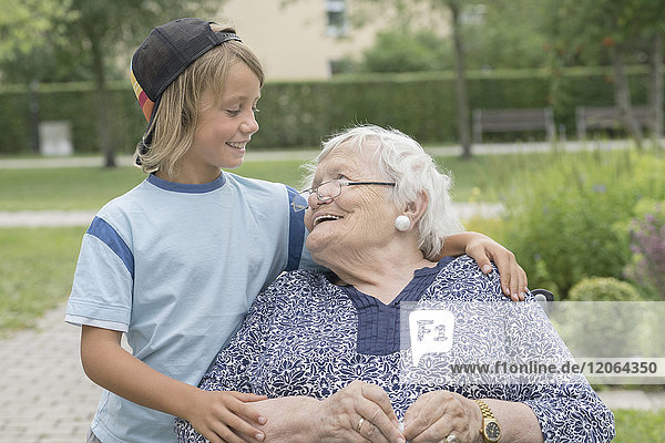 Seniorin im Rollstuhl mit Enkel im Altenheimpark