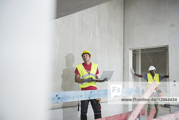 Bauarbeiter mit Laptop auf einer Baustelle