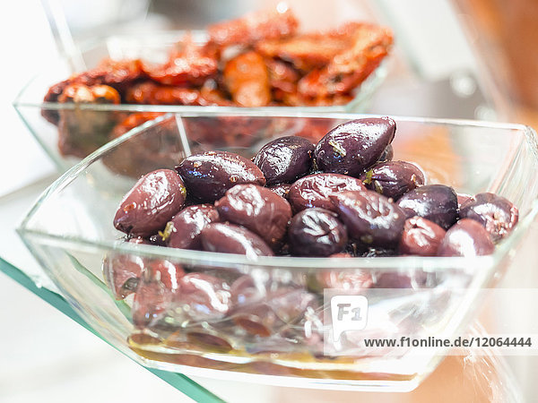 Schwarze griechische Oliven und getrocknete Tomaten in einer Glasschale
