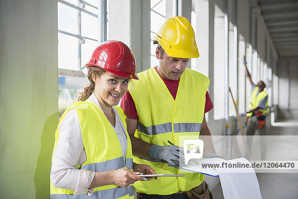Bauarbeiter mit digitalem Tablet und Dokument auf der Baustelle