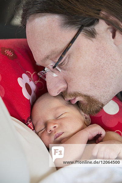 Father kissing his sleeping newborn baby boy