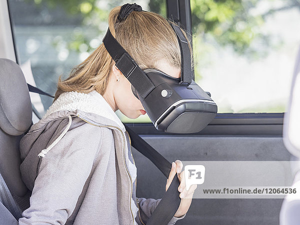 Mädchen mit Virtual-Reality-Headset beim Einstellen des Sicherheitsgurts im Auto