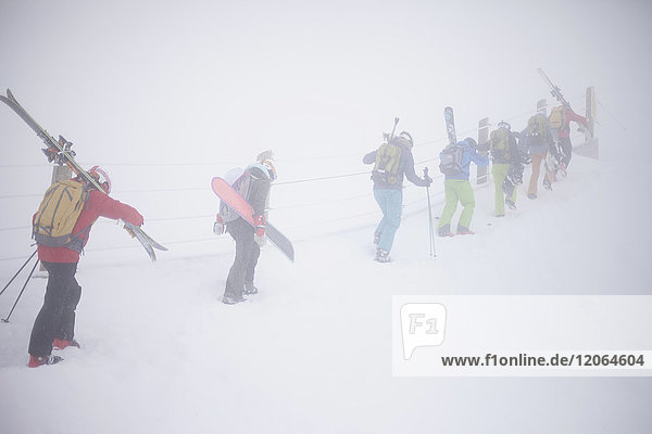 Group if skiers carrying ski gear on mountain slope