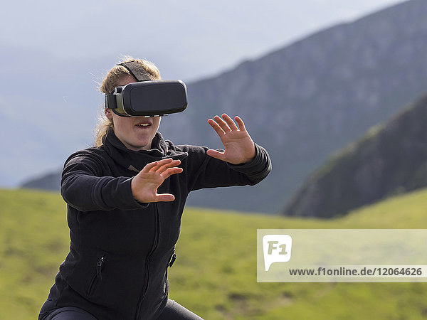 Frau übt Karateschritte mit Virtual-Reality-Brille auf einem Berg
