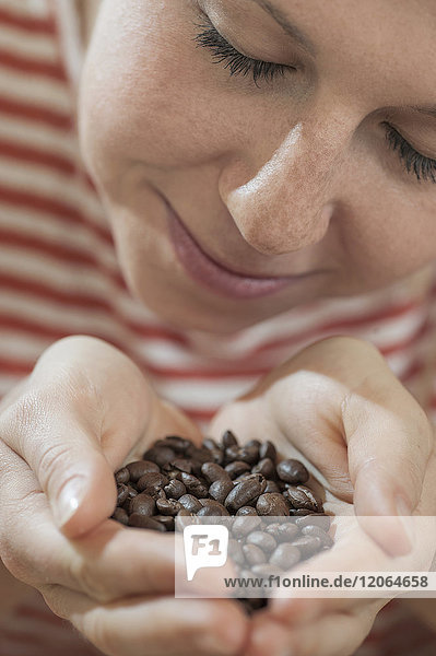 Junge Frau beim Riechen an gerösteten Kaffeebohnen