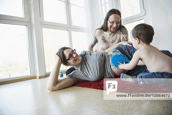 Vater mit Sohn malt mit den Fingern den Bauch der schwangeren Mutter