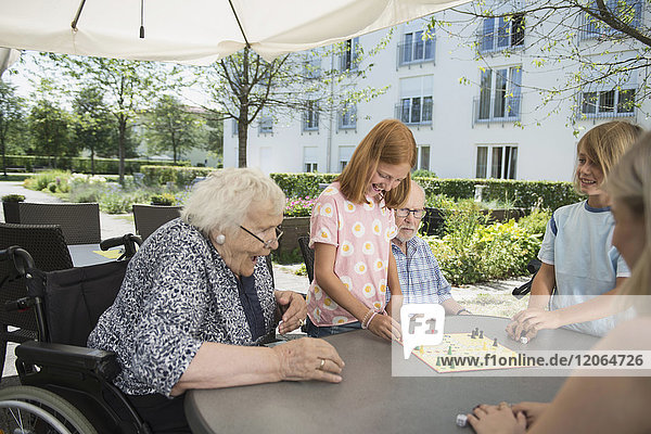 Mehrgenerationenfamilie spielt Brettspiel im Pflegeheim