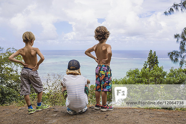 Drei Kinder betrachten den Indischen Ozean von einem Aussichtspunkt aus