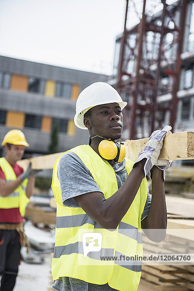 Bauarbeiter tragen Holzbretter auf der Baustelle