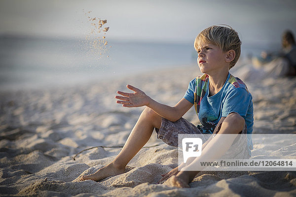 Junge sitzt am Ufer und spielt mit Sand