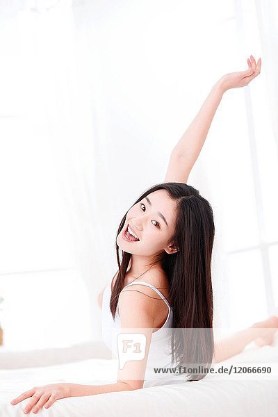 Eine fröhliche junge Frau im Schlafzimmer