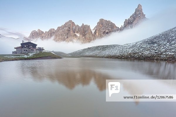 Dolomites Alps Pale di San Martino reflecting on water with clouds Baita Segantini Trentino Alto Adige District Italy.