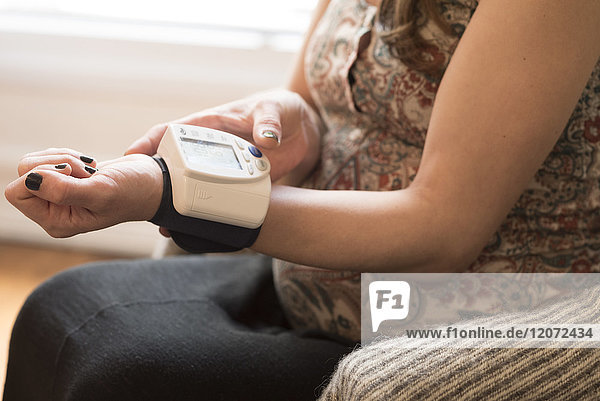 Eine schwangere Frau misst ihren Blutdruck selbst.