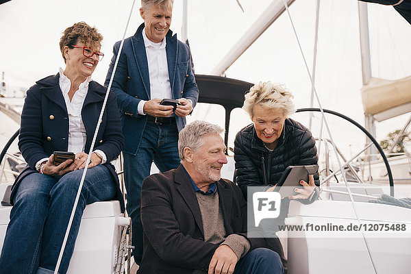 Senior couple using digital tablet while traveling with friends in yacht