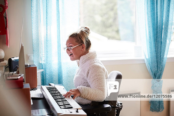 Behinderte junge Frau beim Klavierspielen zu Hause