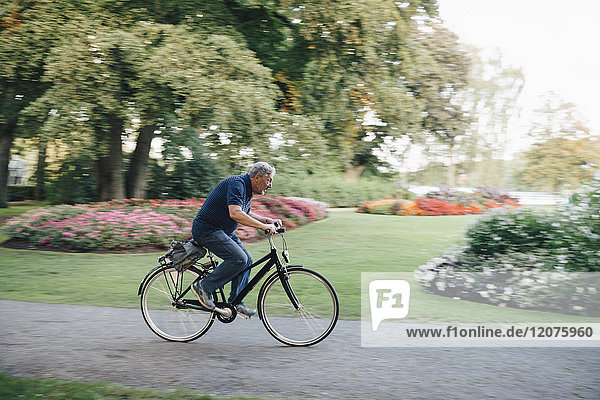 Full length side view of senior man riding bicycle in park