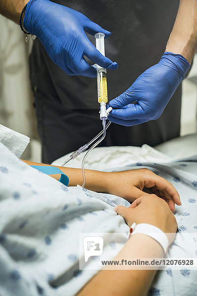 Krankenschwester injiziert Medikament in den Schlauch eines Patienten