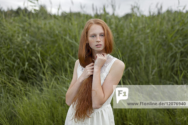 Porträt eines ernsten kaukasischen Mädchens mit Sommersprossen im Feld stehend