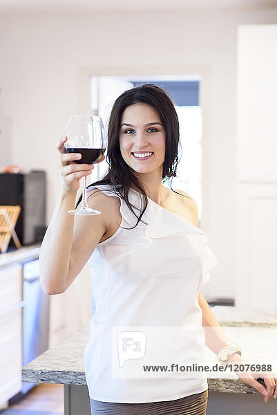 Lächelnde kaukasische Frau  die mit Rotwein anstößt