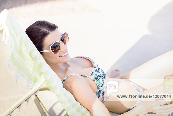 Caucasian woman relaxing in lounge chair holding drink