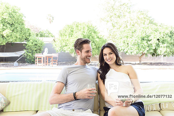 Lächelndes kaukasisches Paar entspannt sich mit kalten Getränken im Freien