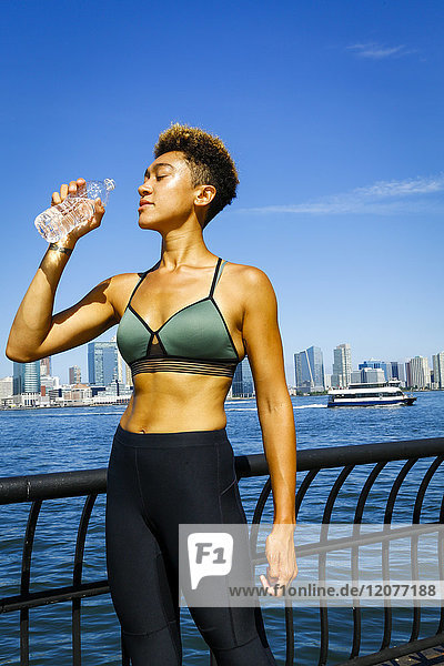 Mixed race woman drinking water at waterfront