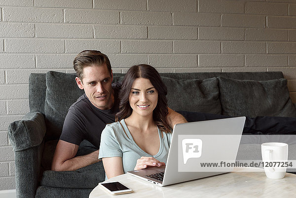 Kaukasisches Paar auf Sofa mit Laptop