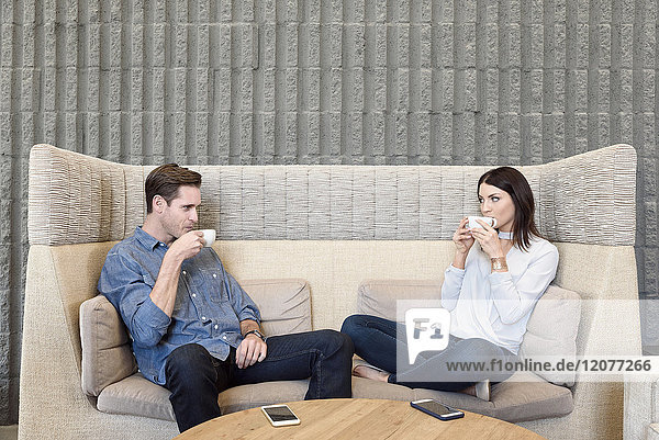 Kaukasisches Paar entspannt sich auf dem Sofa und trinkt Kaffee