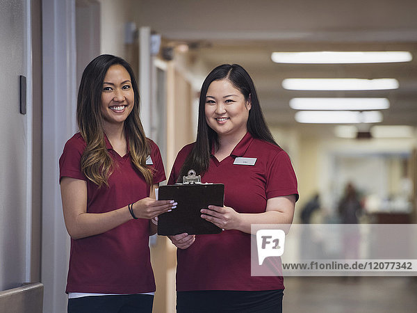 Lächelnde Krankenschwestern mit Klemmbrett im Krankenhaus