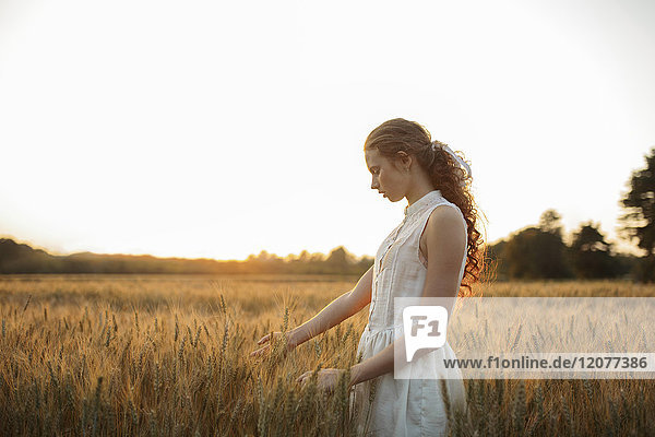 Caucasian girl standing in field of wheat