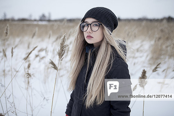 Serious Asian girl standing in field in winter