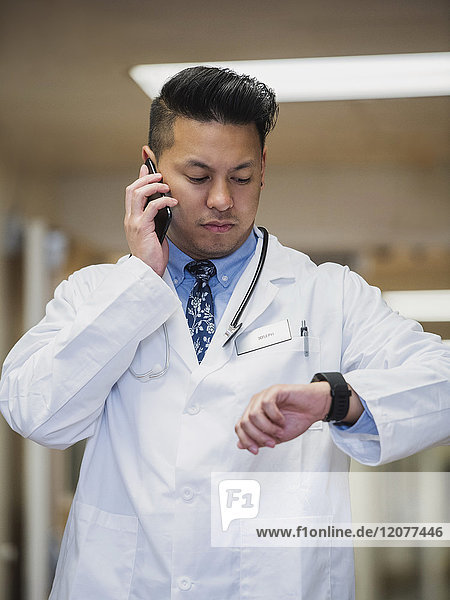 Filipino doctor talking on cell phone and checking the time