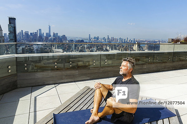 Caucasian man meditating on urban rooftop