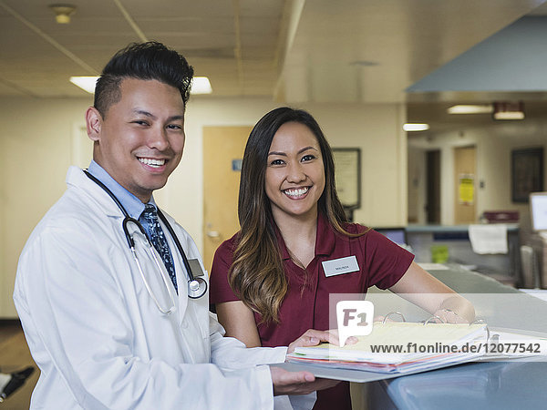 Porträt eines lächelnden Arztes und einer Krankenschwester mit Aktenordner im Krankenhaus
