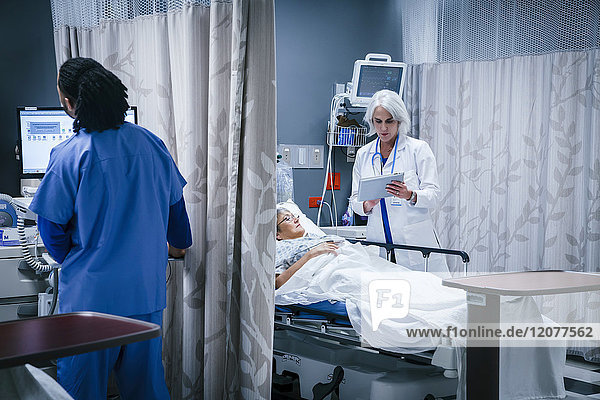 Doctor with digital tablet talking to patient in hospital bed