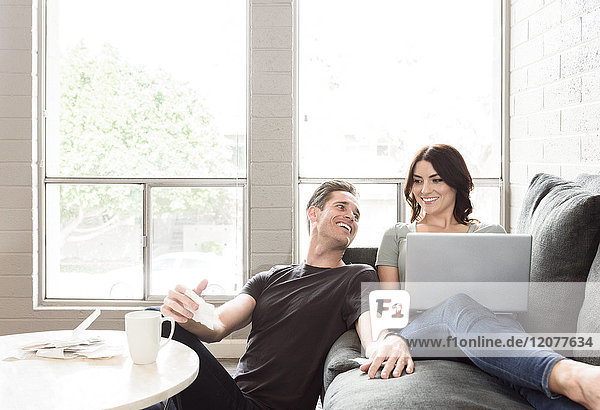 Caucasian couple using laptop on sofa