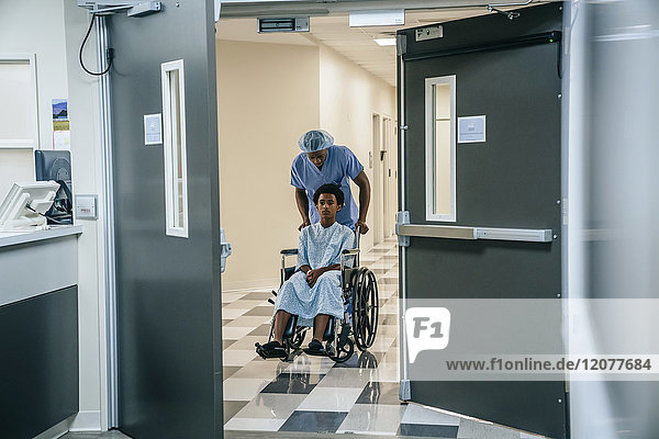 Black nurse pushing boy in wheelchair