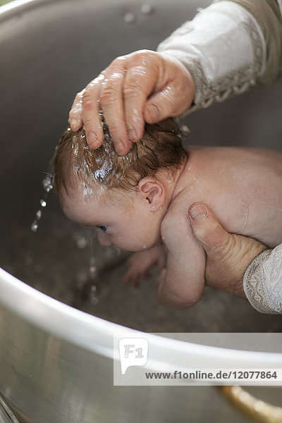 Priester tauft kleines Mädchen mit Wasser